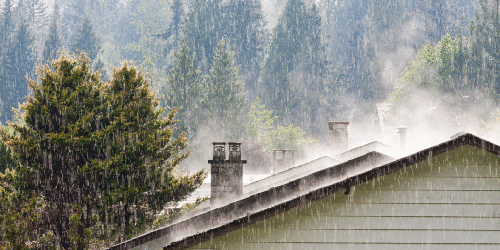 Rain pouring over rooftops in a coastal area, showing the impact of prolonged wet weather that may cause outdoor unit leaking electricity in air conditioning Gold Coast units.
