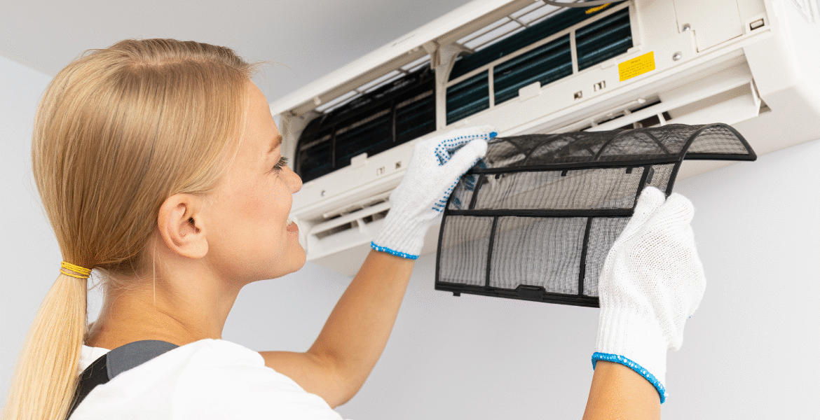 A woman carefully reinstalling a clean air conditioner filter during thanksgiving air conditioner cleaning, illustrating proper air conditioning Gold Coast maintenance.