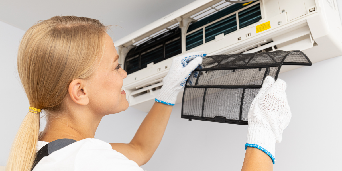 A woman carefully reinstalling a clean air conditioner filter during thanksgiving air conditioner cleaning, illustrating proper air conditioning Gold Coast maintenance.