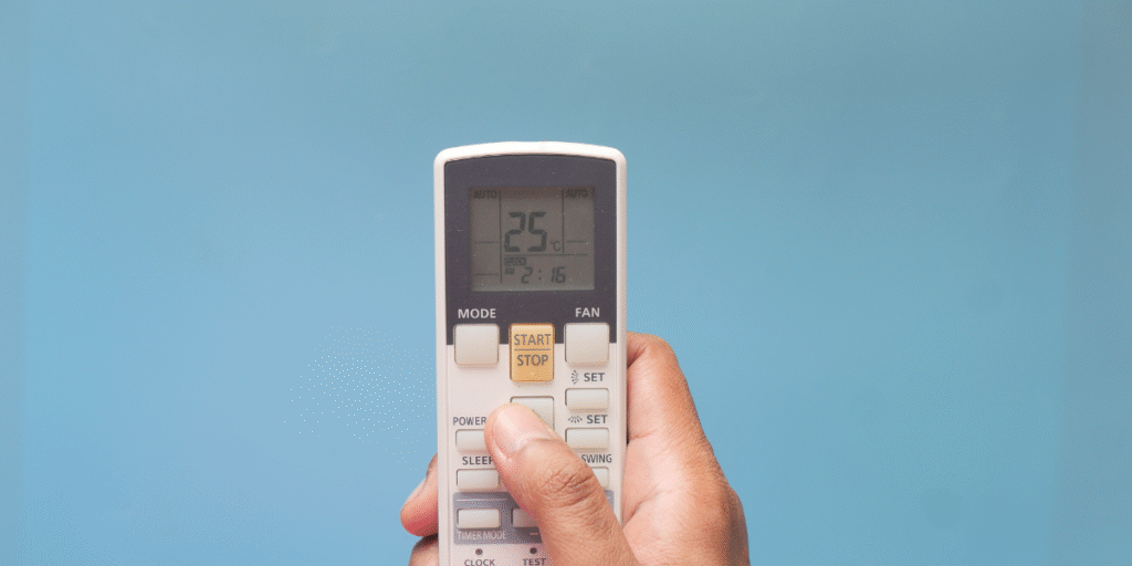 A hand holding an AC remote showing a temperature change, illustrating a thermostat change on its own in a home using air conditioning Gold Coast.