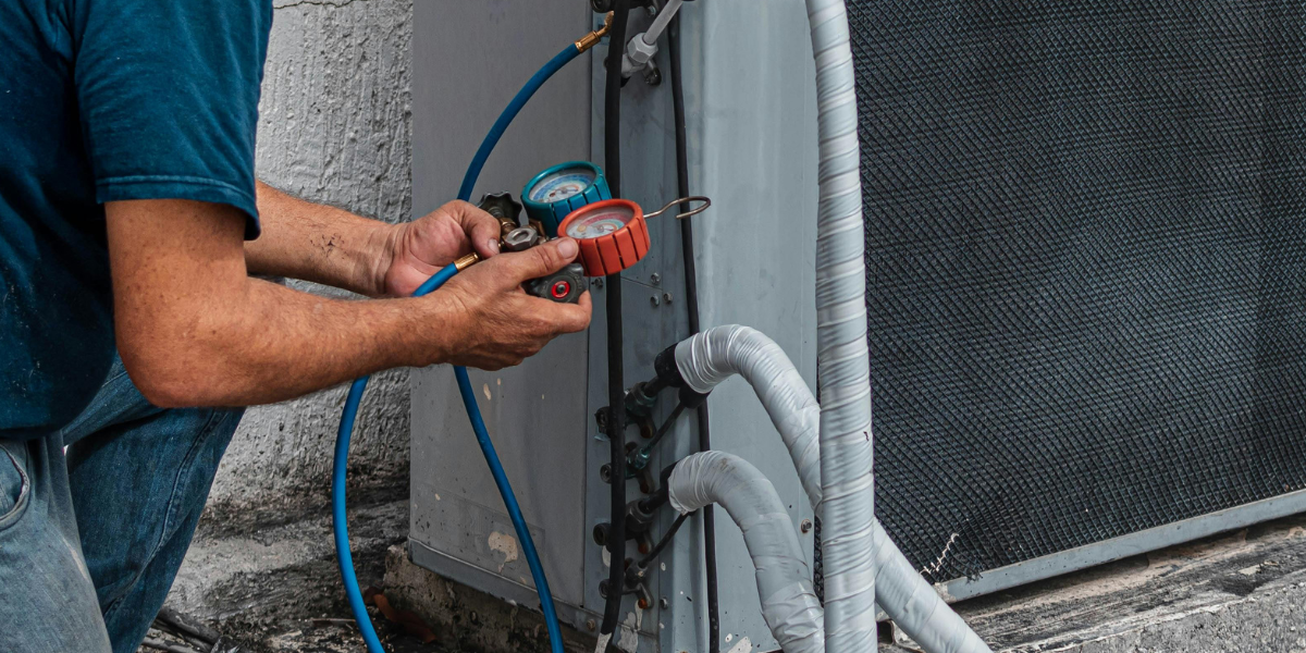 A maintenance worker checking pressure gauges on an outdoor AC system.