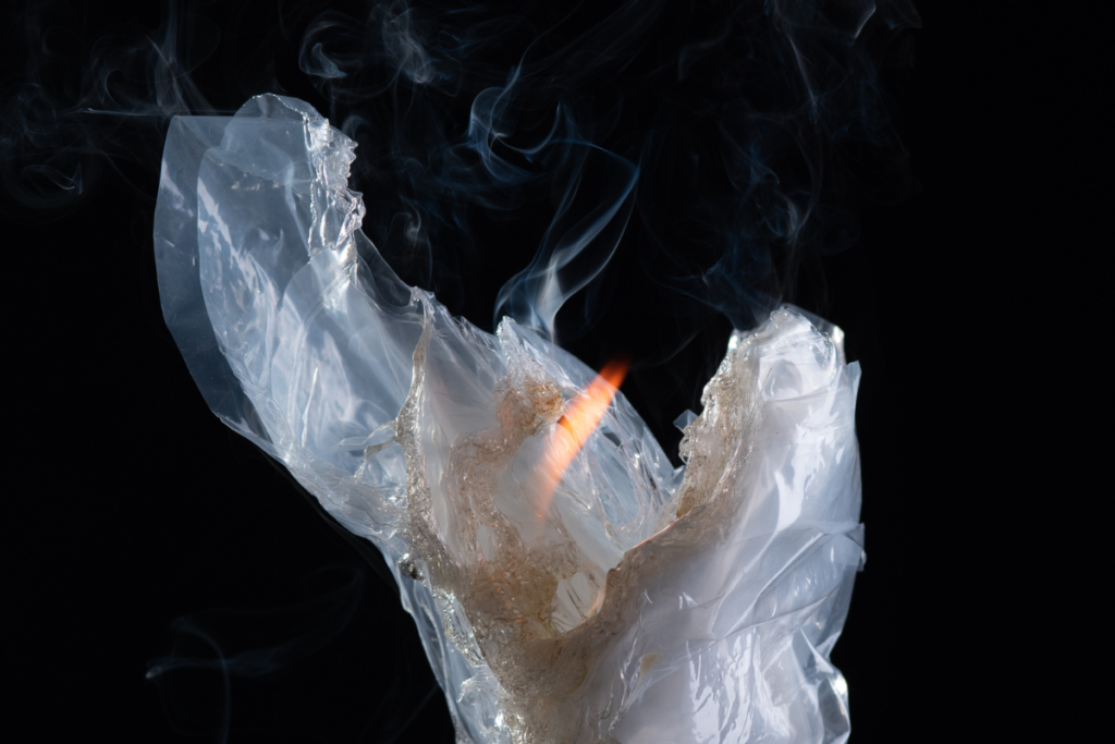 Close-up of melting and burning plastic with visible smoke and flame, representing the dangers of burning plastic fumes that may occur in faulty residential and commercial air conditioning Gold Coast systems.