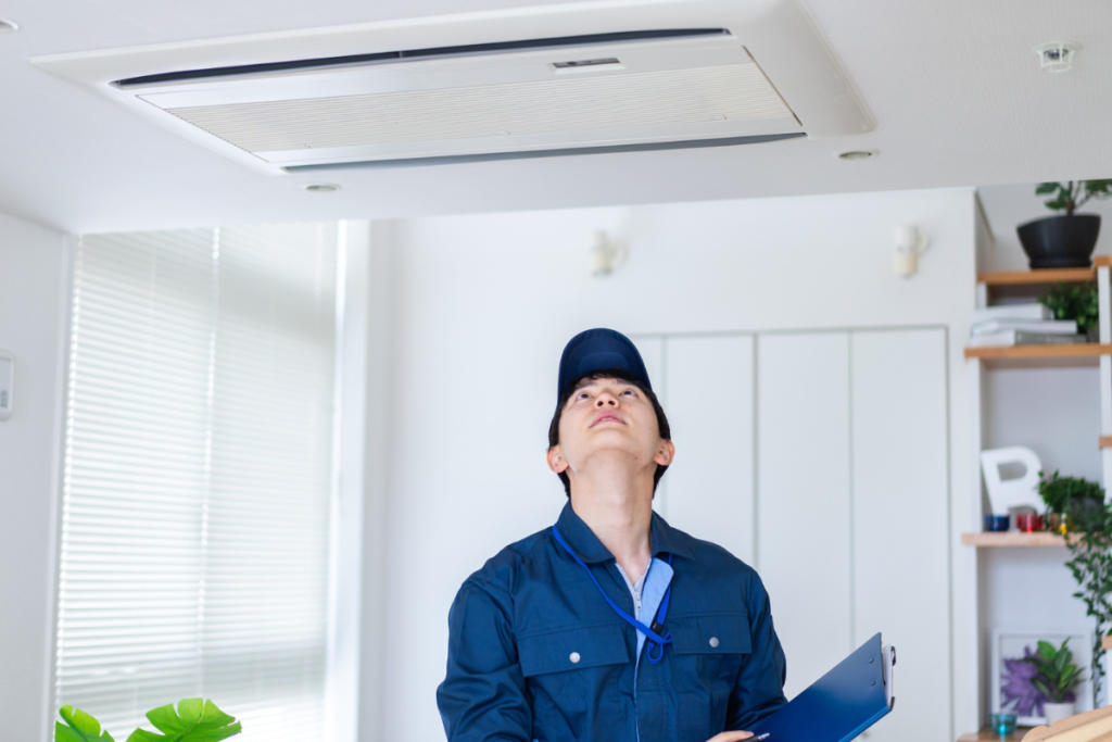 Technician inspecting a ceiling cassette unit linked to abnormal air conditioner noise, often found in large commercial air conditioning Gold Coast systems.