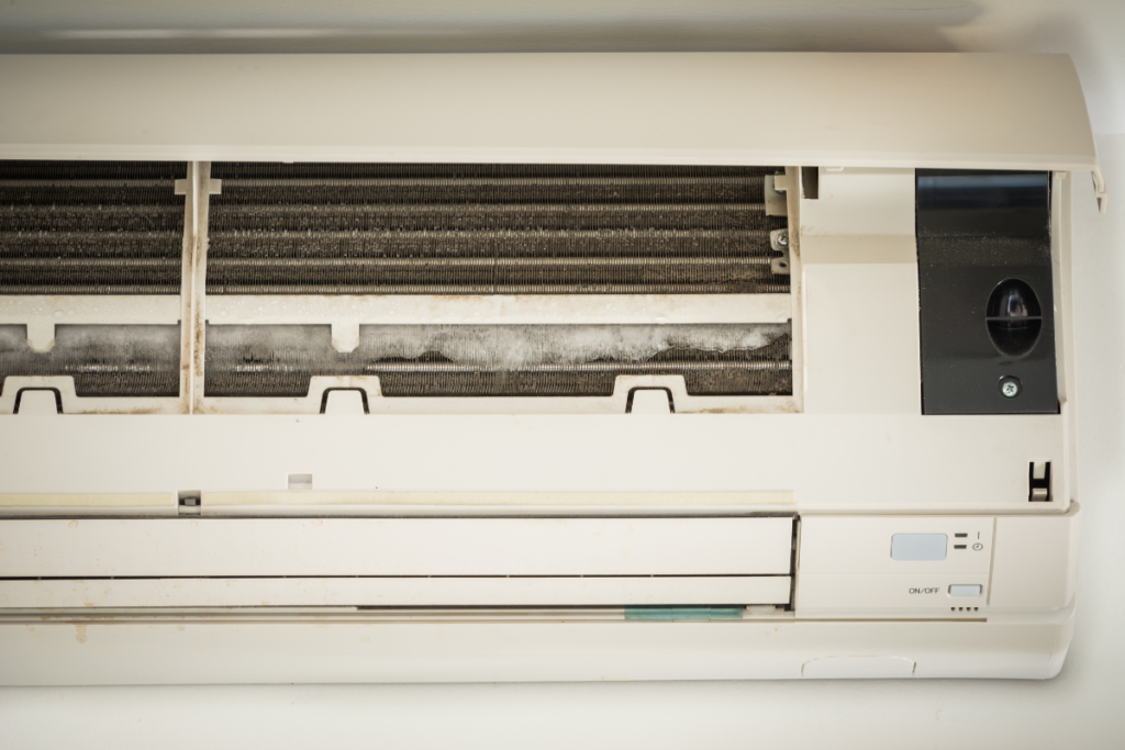 Opened air conditioner indoor unit with visible dust and internal components, highlighting causes of black dust coming out of your air conditioner vent in commercial air conditioning Gold Coast.