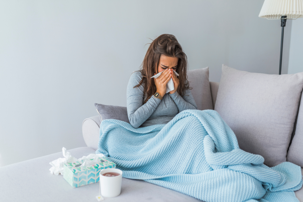 A woman experiencing summer cold symptoms at home, possibly linked to prolonged air conditioning Gold Coast use and dry indoor air.
