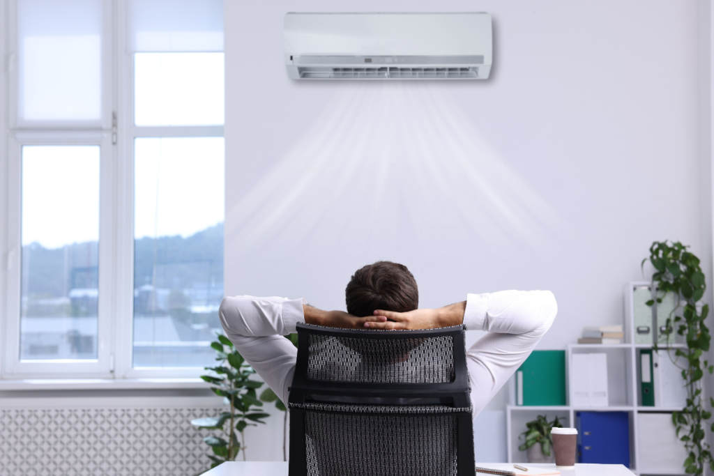 An office worker sitting under commercial air conditioning Gold Coast, highlighting temperature stress that can increase the risk of a summer cold.