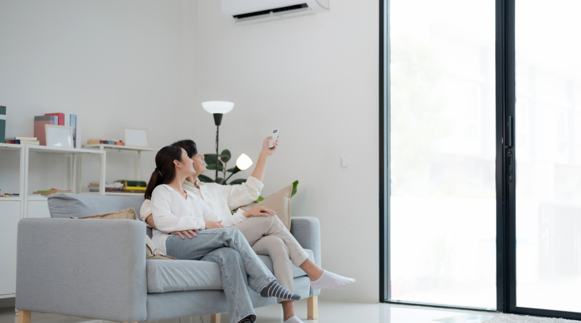 Couple adjusting remote to fix autumn comfort problems at home, addressing what is the common problem with an air conditioner in fall, air conditioning Gold Coast.