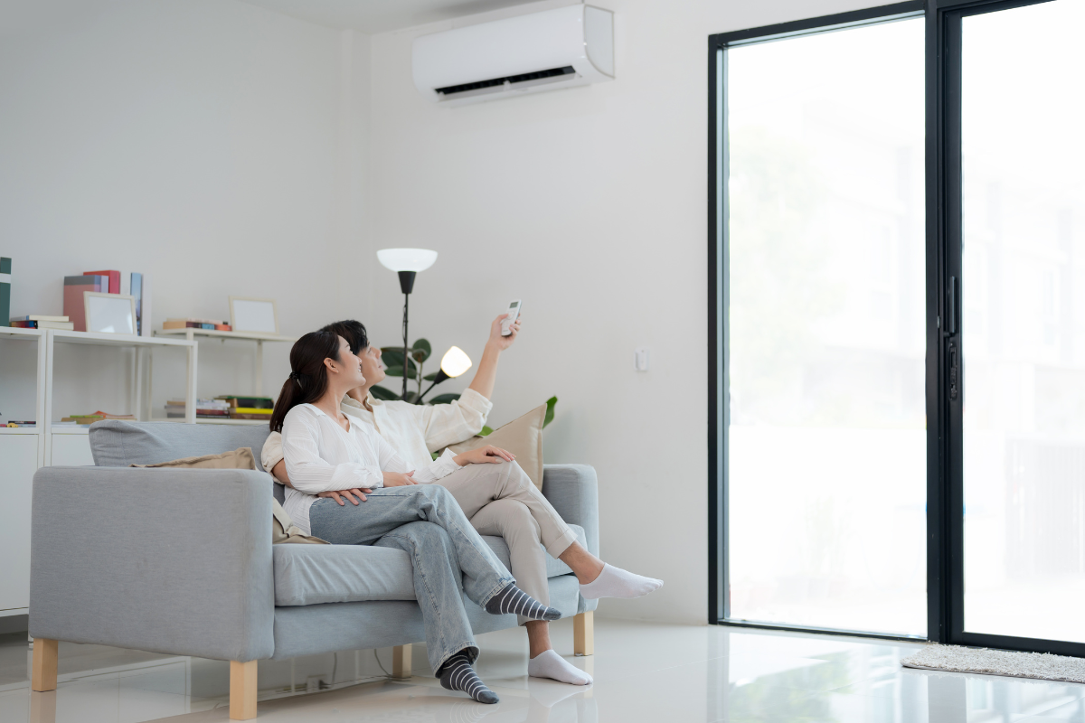 Couple adjusting remote to fix autumn comfort problems at home, addressing what is the common problem with an air conditioner in fall, air conditioning Gold Coast.