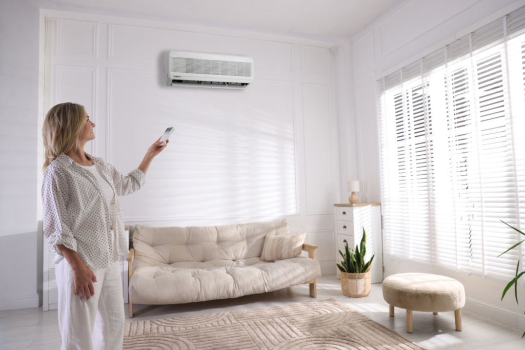 Woman controlling split system air conditioner in a bright living room, showing how to save power during hot weather with air conditioning Gold Coast.