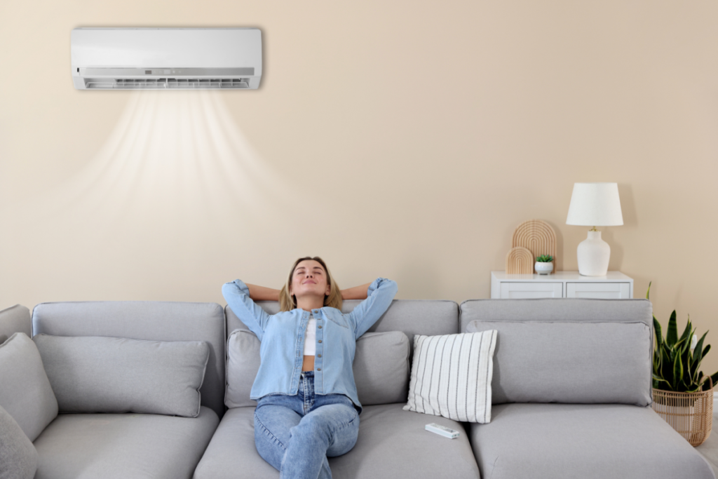 Woman relaxing comfortably under split system while adjusting summer AC settings and asking what temperature should I set my air conditioner in fall at night in air conditioning Gold Coast property.