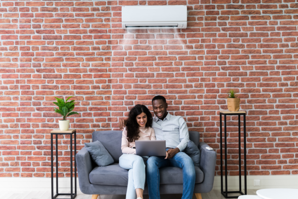 Couple relaxing under split system in modern living room, showcasing LG vs Panasonic comparison among the Best air conditioners in Australia for residential and commercial air conditioning Gold Coast needs.