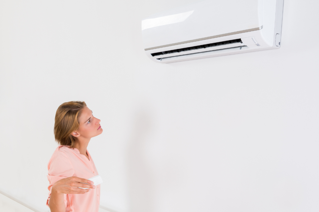 Homeowner checking wall-mounted unit while considering LG vs Panasonic, two of the Best air conditioners in Australia for air conditioning Gold Coast properties and residential air conditioning Gold Coast upgrades.