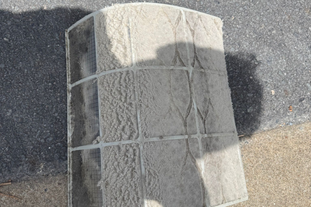 A heavily clogged and dusty air filter removed during a routine autumn maintenance service for residential air conditioning gold coast. Proper filter cleaning is essential to maintain system efficiency before winter.