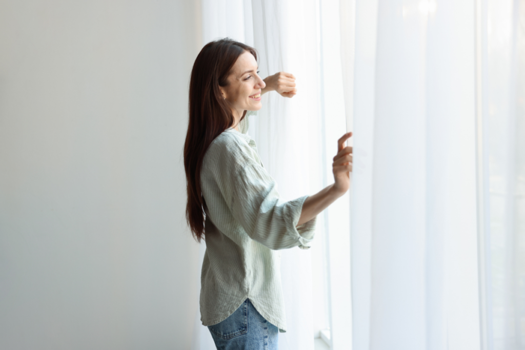 Woman opening the window to improve airflow and reduce humidity, air conditioning Gold Coast home