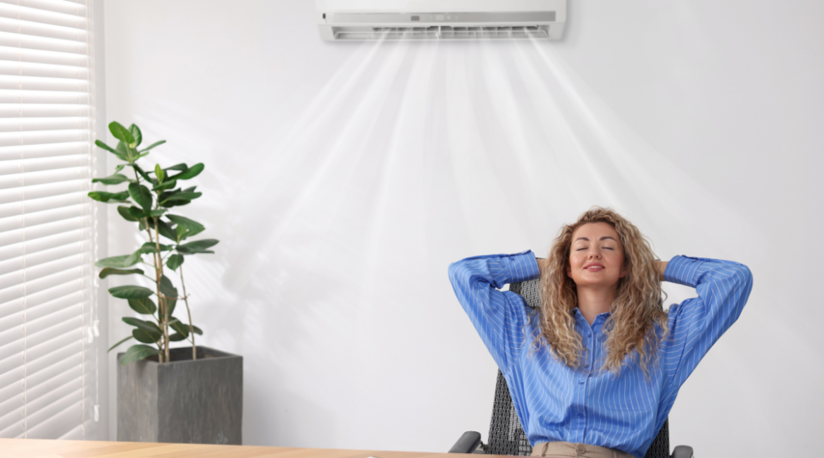 Woman relaxing under wall-mounted air conditioner showing how running your AC will reduce humidity, demonstrating how to make AC remove more humidity in air conditioning Gold Coast homes
