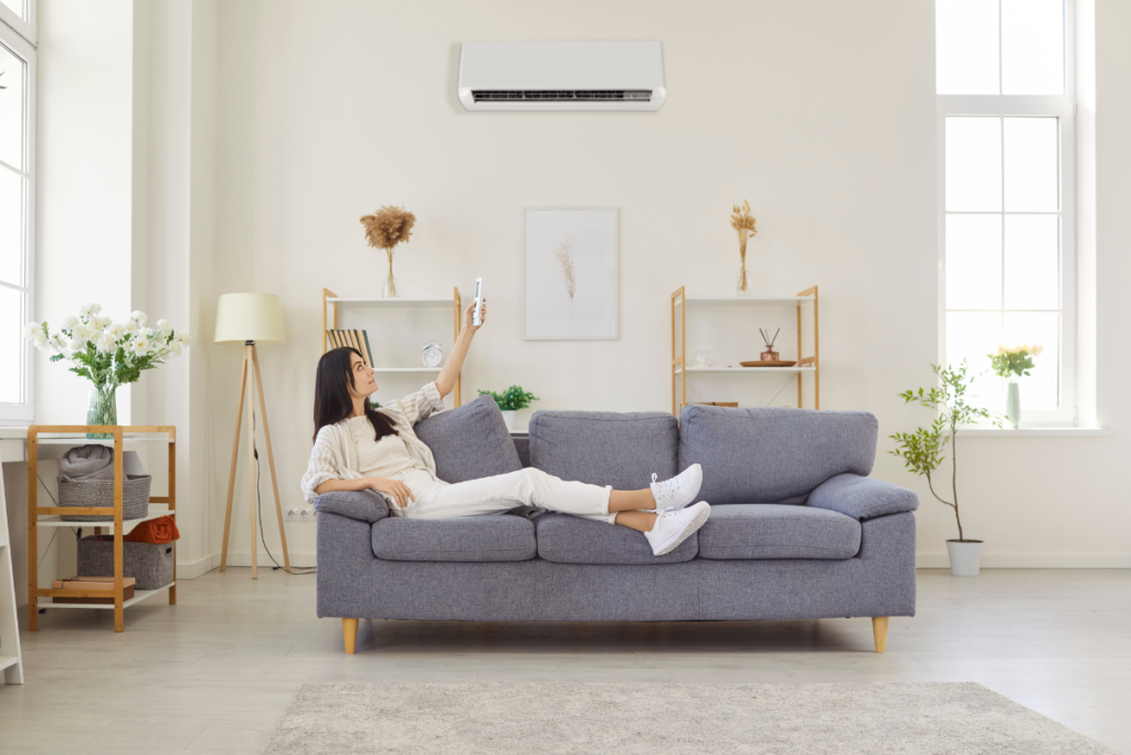 Run AC dry mode in a modern living room as a woman adjusts settings, showing how to manage humidity efficiently with air conditioning Gold Coast for residential and commercial air conditioning Gold Coast.