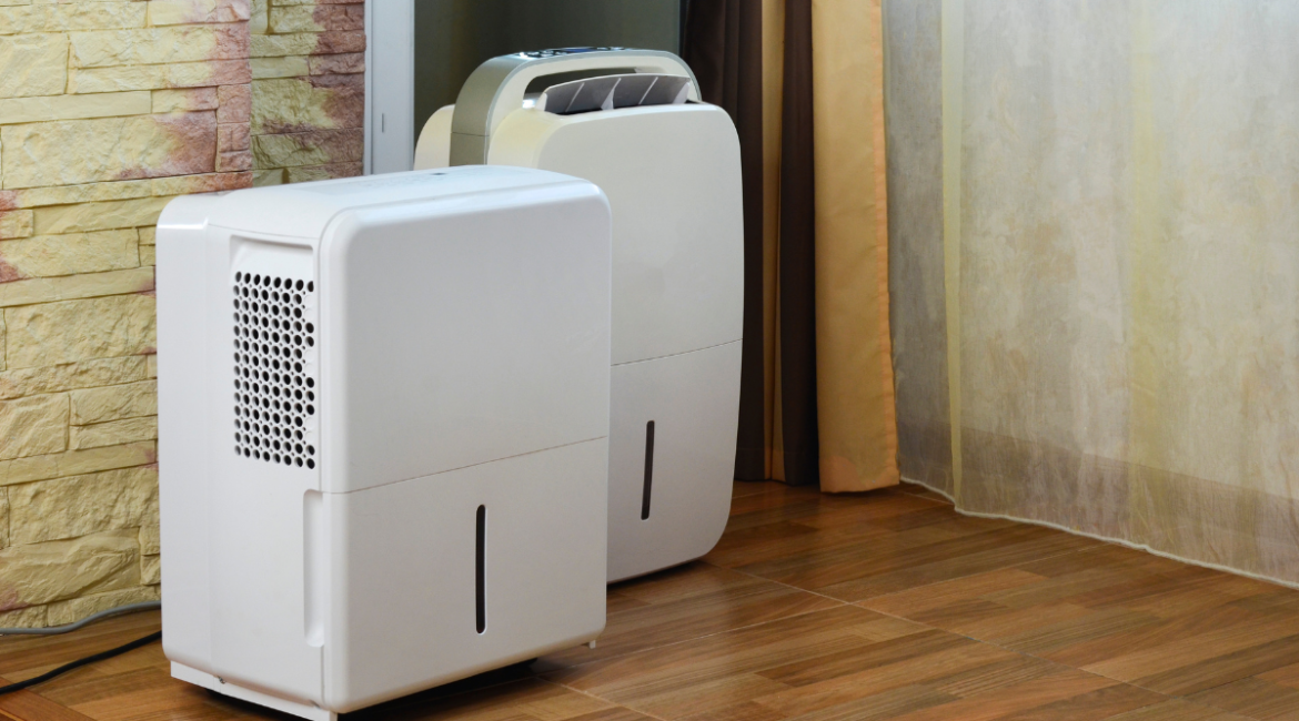 Two portable white dehumidifiers standing on a wooden floor, ideal for larger homes or commercial air conditioning Gold Coast spaces that use a dehumidifier to prevent mold.