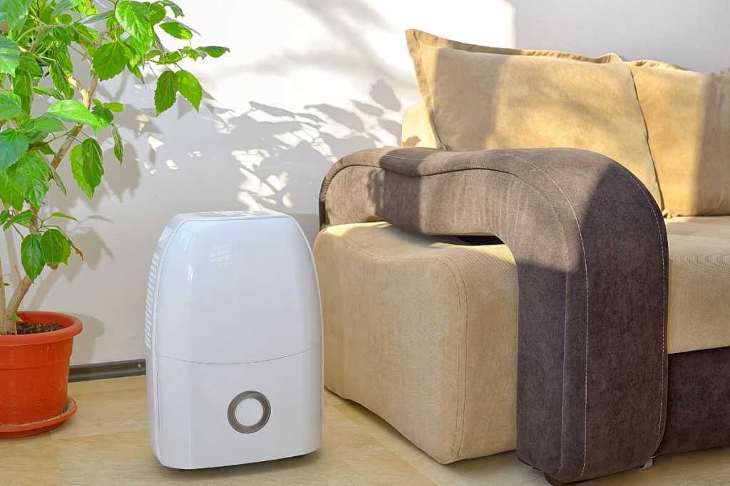 A portable dehumidifier in a living room; homeowners often wonder if it is cheaper to run aircon or dehumidifier for residential air conditioning Gold Coast moisture control.