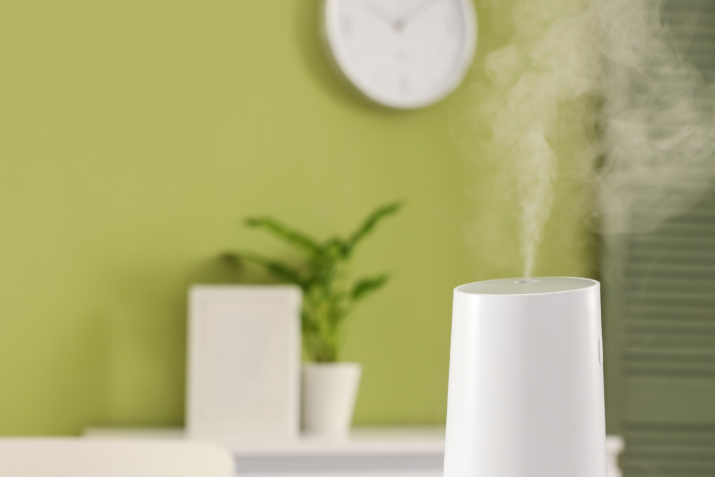 A standalone white ultrasonic humidifier emitting a plume of visible mist in a cozy living space, contrasted against a simpler method like a bowl of water. A better solution than a bowl of water for managing dry air from residential air conditioning gold coast.