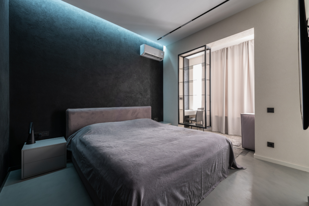 A peaceful bedroom with modern furniture, featuring a modern white AC unit integrated into a black accent wall with blue backlighting. This scene relates to optimal comfort for sleeping in an AC room, which can make air dry without correct usage of residential air conditioning gold coast.
