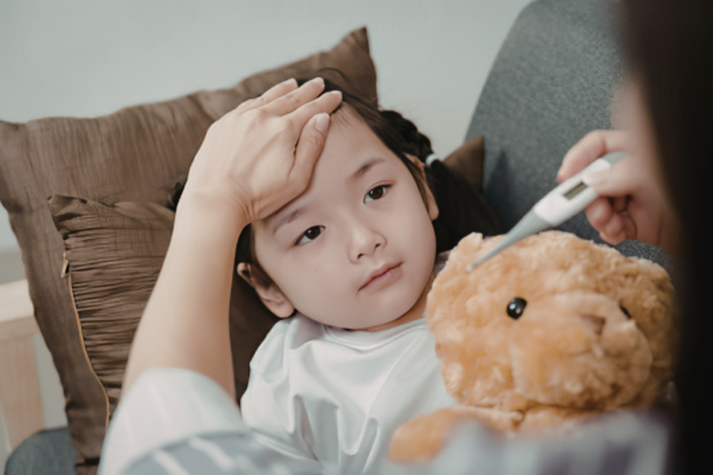 A mother checking her little girl's fever while she hugs a teddy bear in a clinic or daycare space, kept comfortable by reliable commercial air conditioning Gold Coast services.