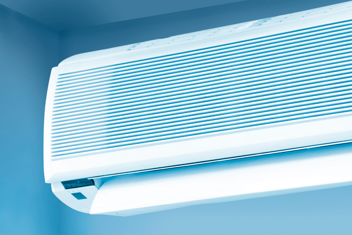 Close-up of a sleek, modern white indoor AC unit, angled against a soft blue wall. Discussing how residential and commercial air conditioning gold coast systems can make air dry, especially when not regularly maintained.