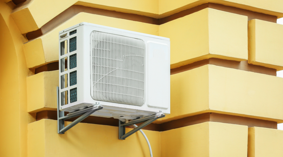 A white Daikin outdoor unit mounted on a yellow textured wall, demonstrating a high-quality residential air conditioning Gold Coast installation capable of Daikin Heat Mode for year-round comfort.