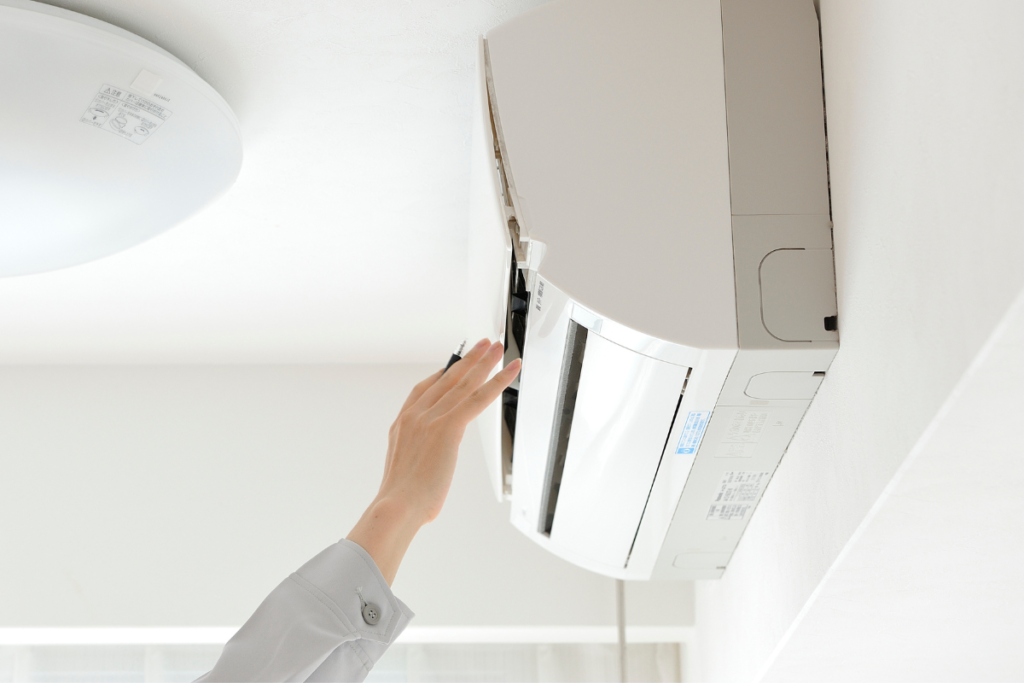 A hand pointing a remote control to operate a wall-mounted indoor unit, highlighting everyday air conditioning Gold Coast usage before upgrading to a smart Panasonic ECO AI system.