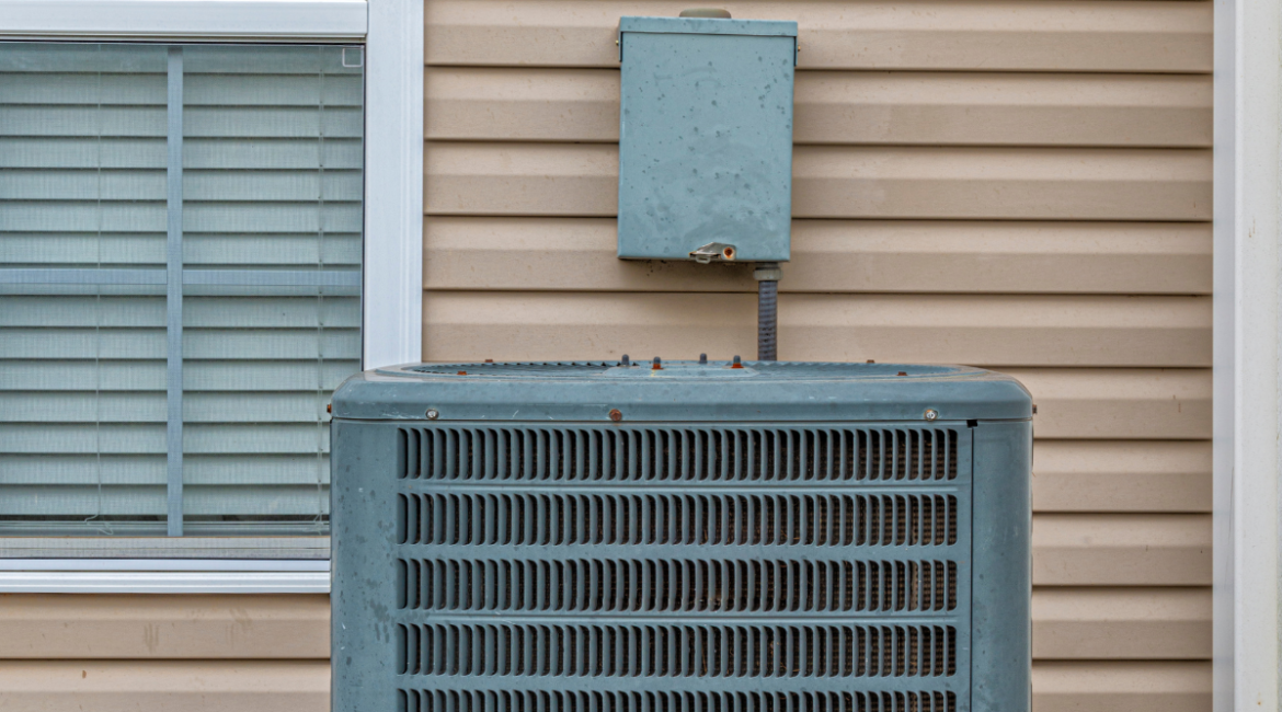 A residential air conditioning condenser unit installed outside a house with beige siding, highlighting the importance of regular air conditioning maintenance gold coast to keep electricity bills low.