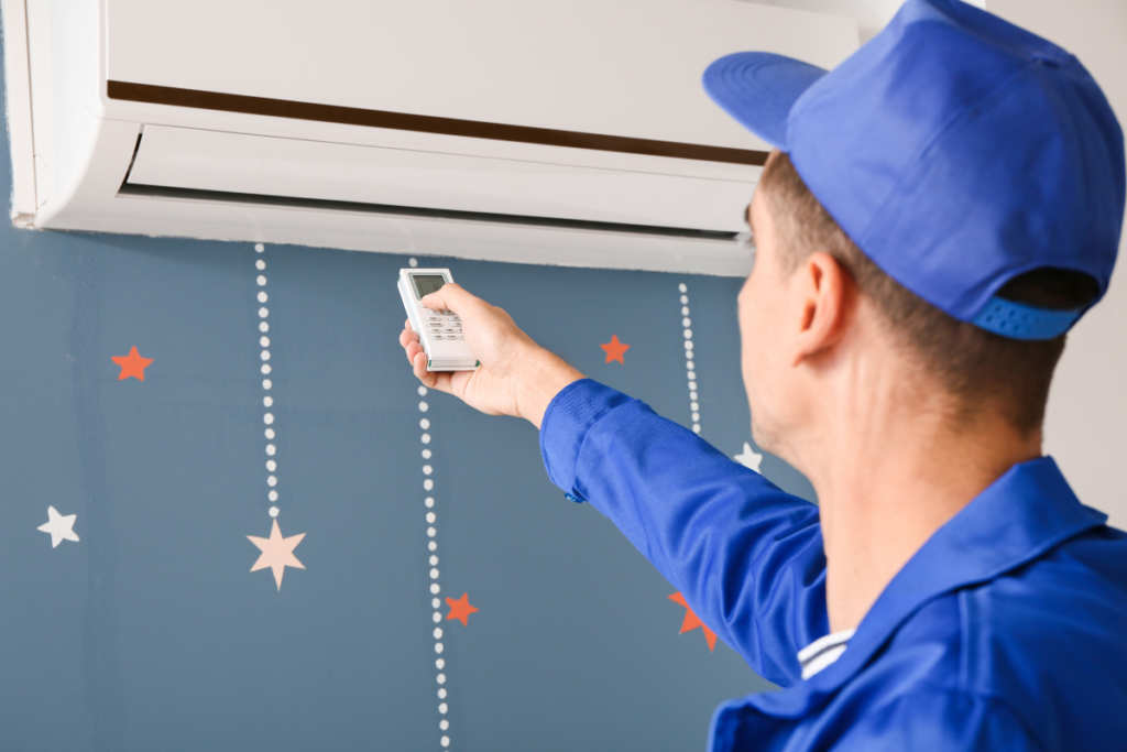 A technician in a blue uniform using a remote control to test a wall-mounted unit during a residential air conditioning Gold Coast service. This routine aircon maintenance ensures the system is cooling efficiently.