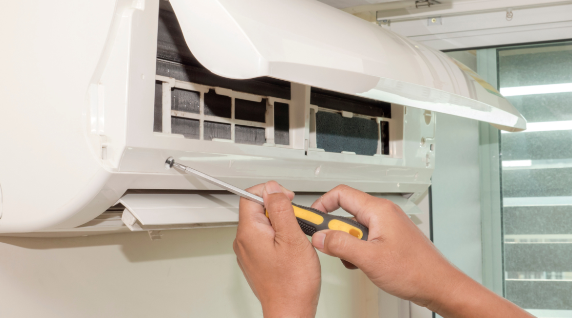 Close-up of a technician's hands using a screwdriver to open a split system for air conditioning maintenance Gold Coast. Regular aircon maintenance helps prevent breakdowns and improves indoor air quality.