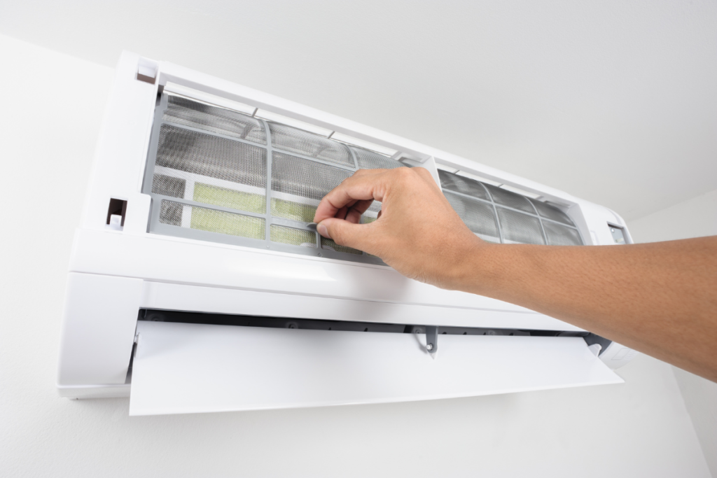 Person cleaning the filter of a residential air conditioning Gold Coast system, a crucial part of air conditioning maintenance gold coast.