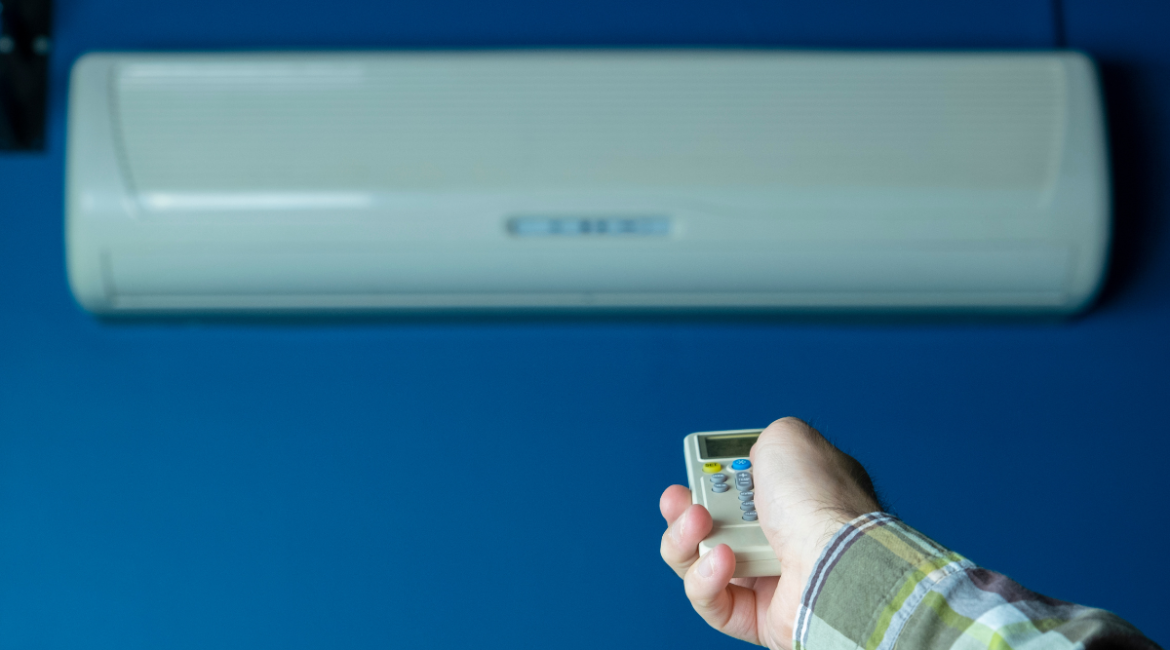 Hand adjusting the temperature for whole house using a remote for an air conditioning Gold Coast unit.