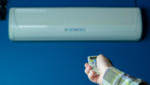 Hand adjusting the temperature for whole house using a remote for an air conditioning Gold Coast unit.