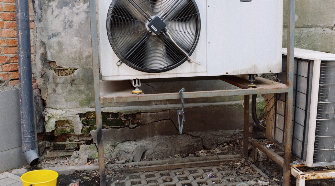 Industrial outdoor HVAC unit with a large spinning fan blade next to a brick wall, an essential commercial setup that needs proactive ac maintenance in gold coast to prevent sudden white steam or failures.