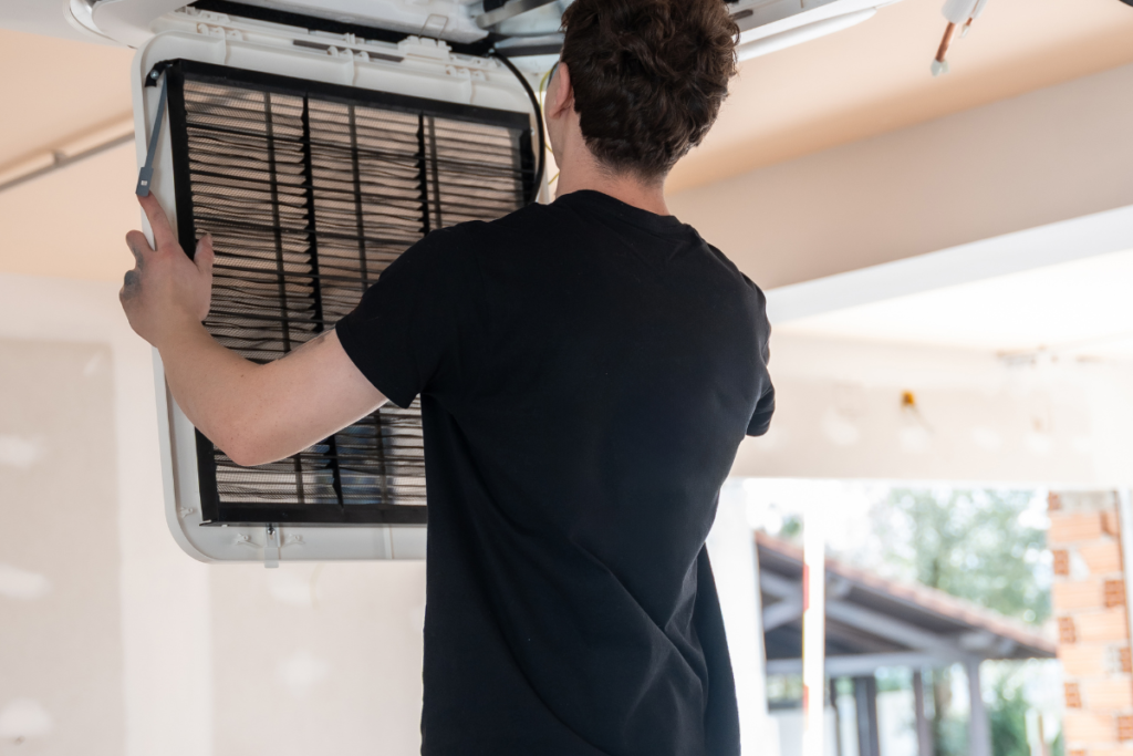 HVAC technician cleaning an indoor air conditioner filter before a new ducted air conditioning installation, supporting homeowners upgrading from older systems and exploring interest free AC finance options.