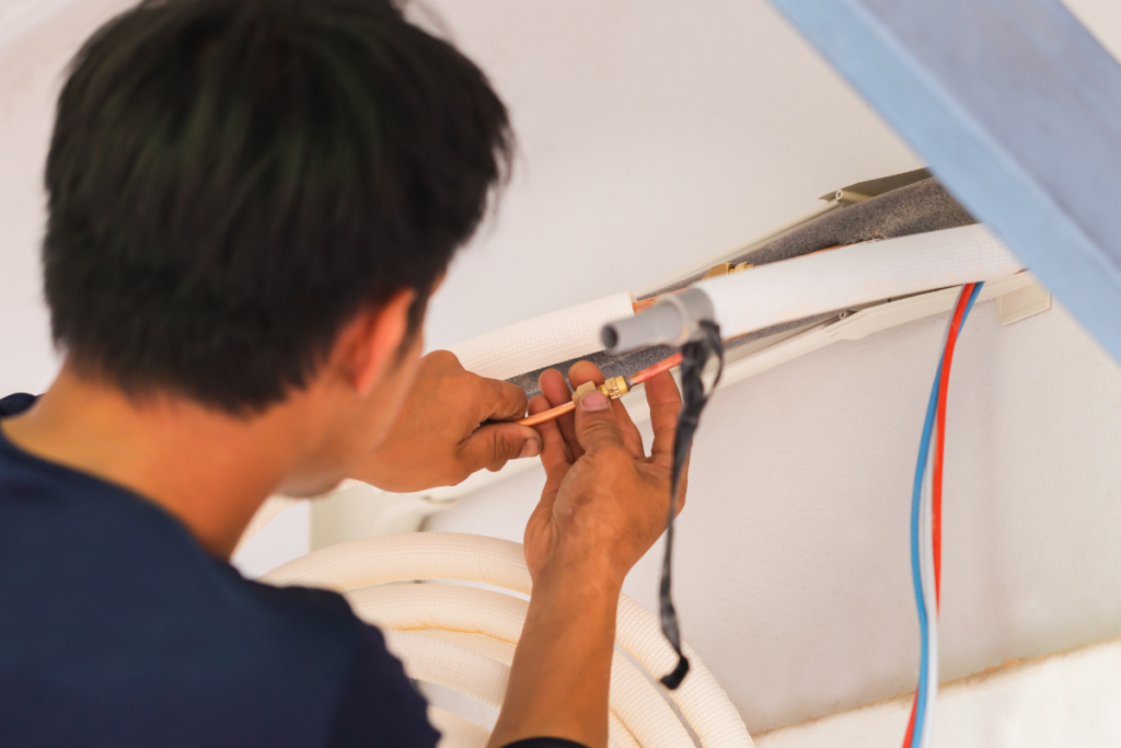 Close-up of a technician working on HVAC piping, representing professional hotel air conditioning installation and EOFY equipment upgrade services.
