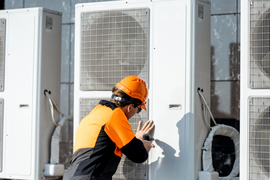An electrician wearing safety gear performing commercial air conditioning installation on the Gold Coast for an EOFY project.