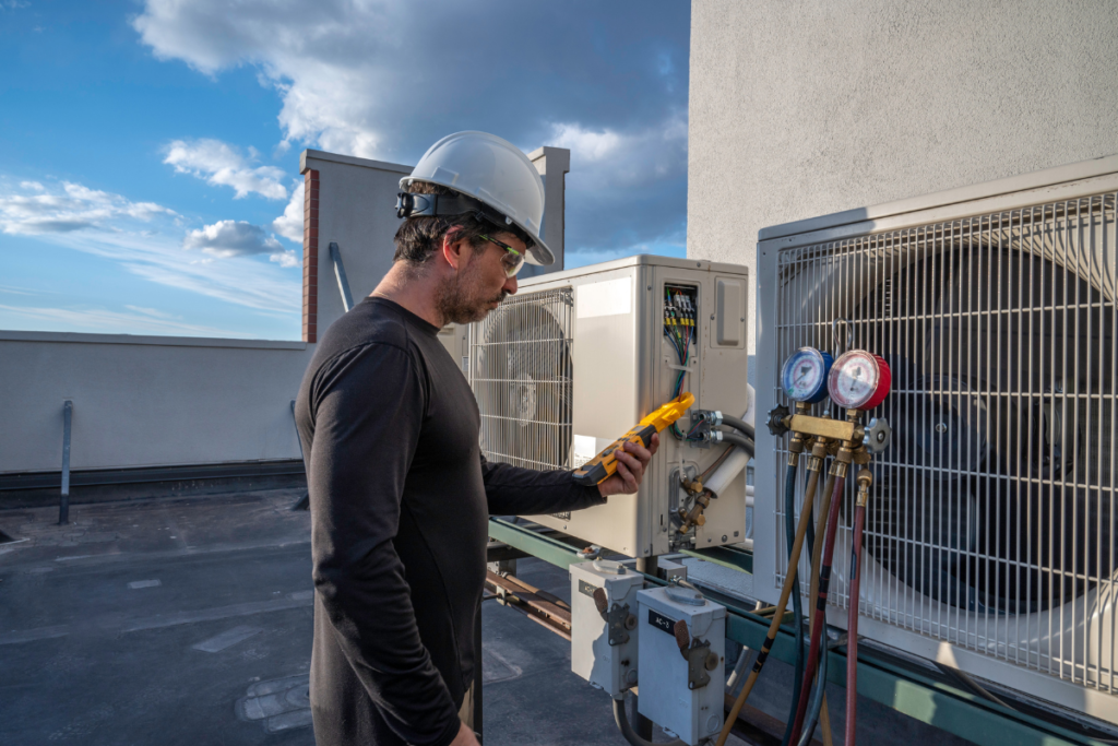 Technician performing preventative hotel HVAC maintenance on a rooftop VRV air conditioning system, checking refrigerant pressure to support hotel AC breakdown prevention and reduce costly commercial air conditioning repair on the Gold Coast.