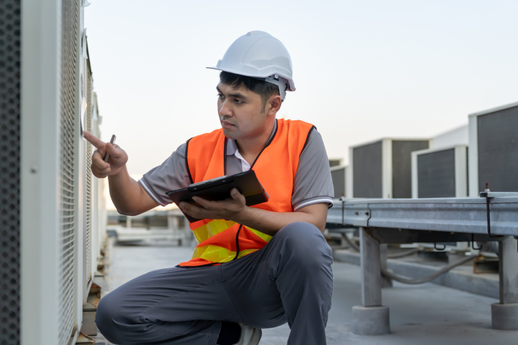Maintenance technician inspecting a commercial air conditioning unit during scheduled preventative hotel HVAC maintenance, supporting hotel AC breakdown prevention and long-term system reliability.