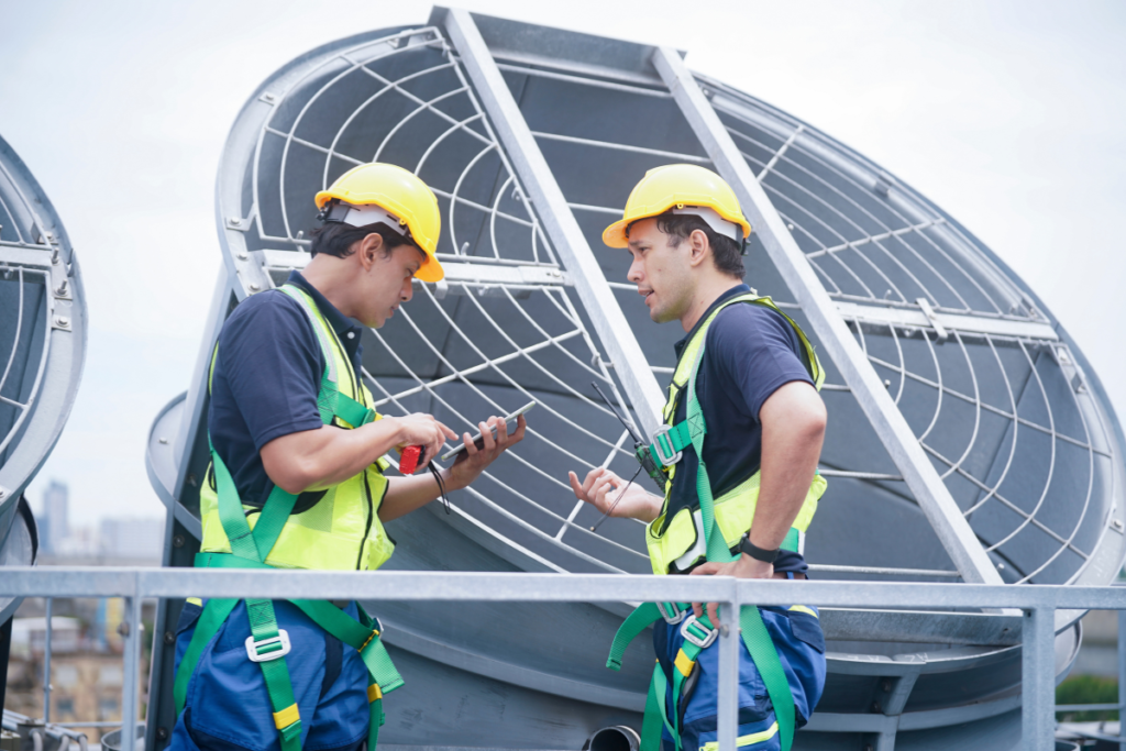 Two HVAC engineers reviewing system diagnostics on a tablet during regular HVAC maintenance for a large commercial facility.