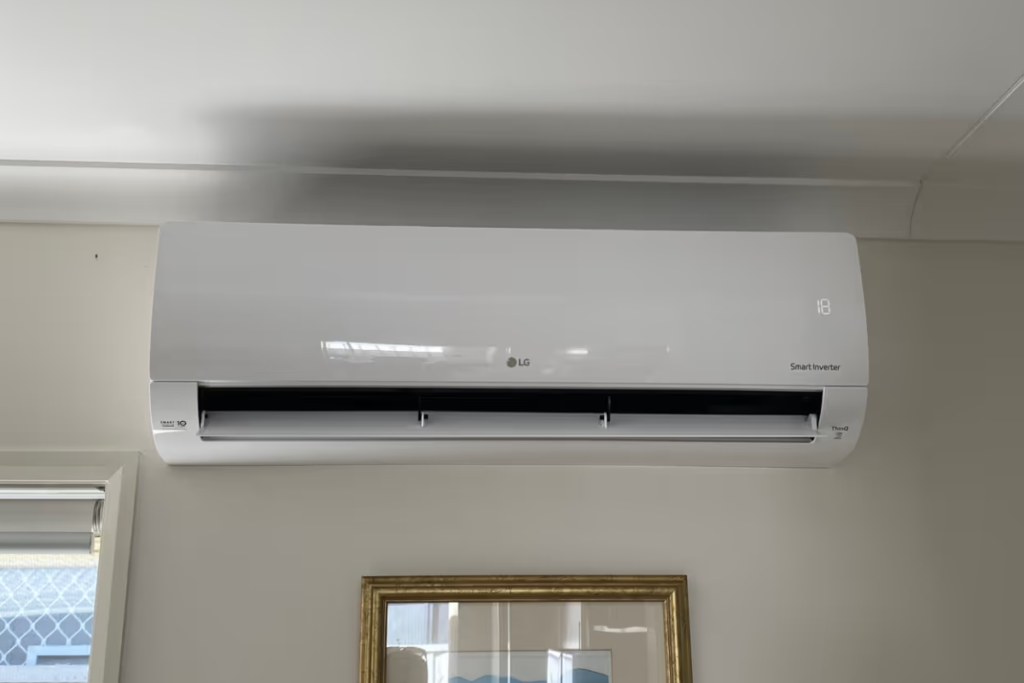 White LG Smart Inverter split system above a framed picture in a living room, a popular LG split system Gold Coast homes choose.