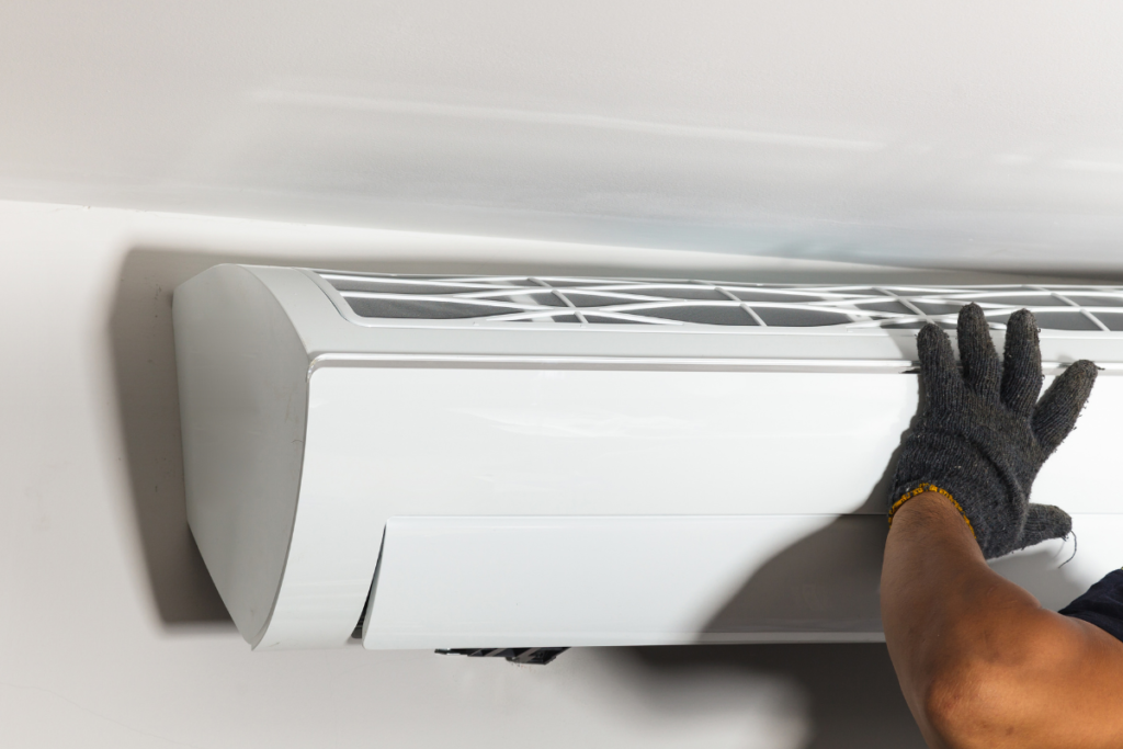 Technician fitting the front panel onto an indoor split system air conditioner after installation