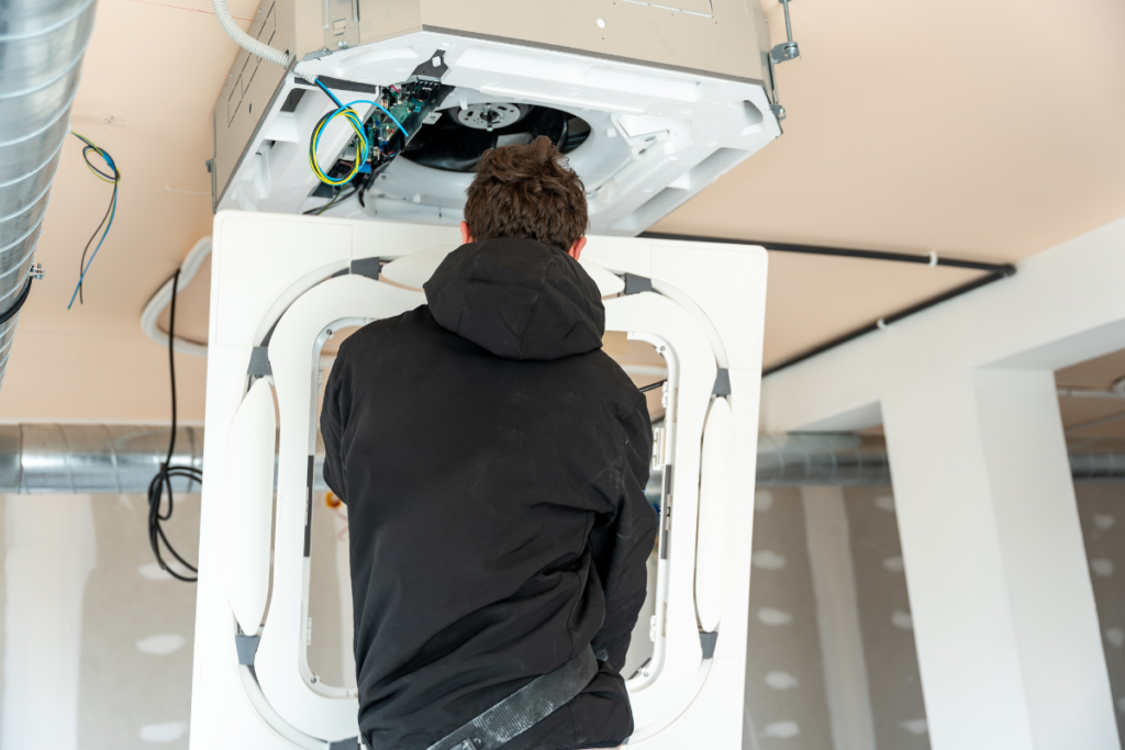 Technician wiring a ceiling cassette unit during a commercial air conditioning installation Gold Coast businesses book in winter