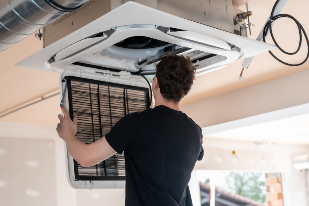 Technician servicing the filter on a reverse cycle air conditioning Gold Coast system ahead of the winter season