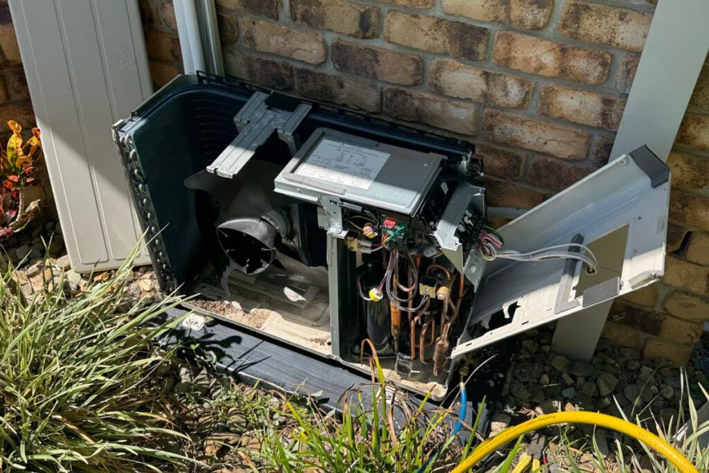 Technician performing an air conditioning service Gold Coast on an outdoor unit to find the cause of low refrigerant