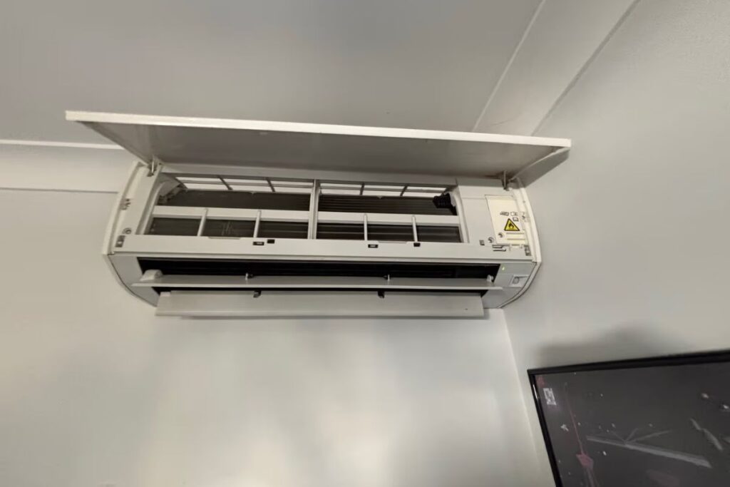 Wall-mounted split system air conditioner opened up for an air conditioning repair on the Gold Coast, showing filters and coils inside.