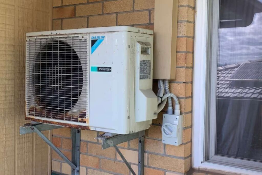 Ageing Daikin outdoor air conditioning unit with rust on the bracket, overdue for a pre-summer service on the Gold Coast.
