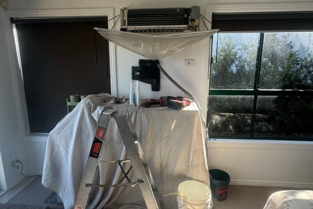 Aircon service on a Gold Coast wall-mounted split system, with a cleaning bag catching water during a professional clean.
