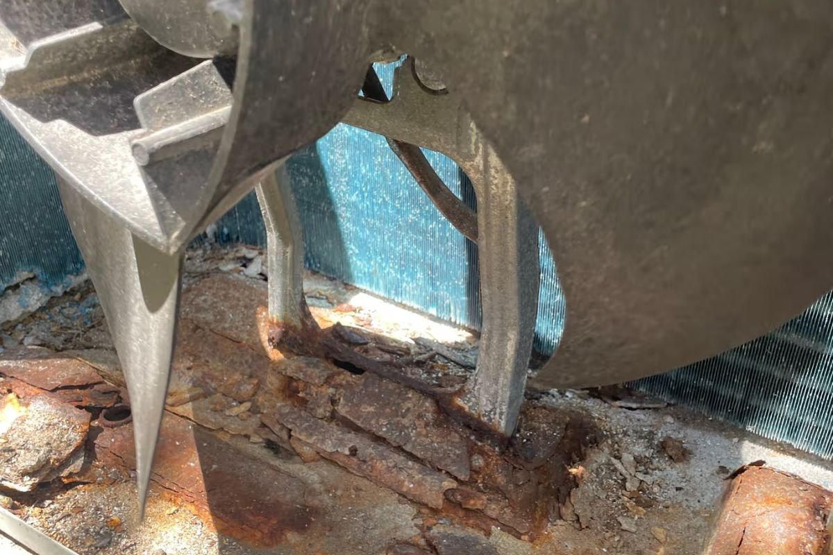 Rusted fan mount and base inside a coastal outdoor unit — salt damage that air conditioning Gold Coast experts see near the beach